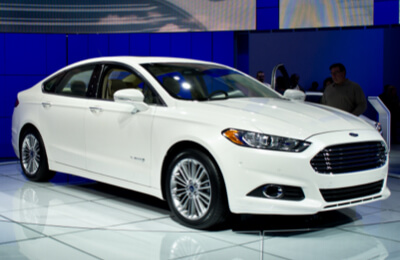 White Ford Fusion Hybrid on display in a showroom, highlighting its modern design and eco-friendly hybrid technology.
