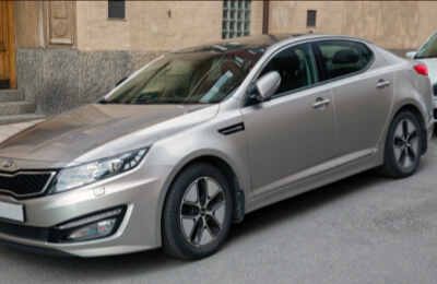 Silver Kia Hybrid parked on a city street, featuring sleek design and efficient hybrid technology.
