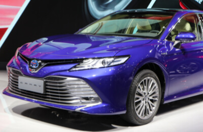 Blue Toyota Camry Hybrid showcased in a showroom, emphasizing its stylish design and advanced hybrid features.